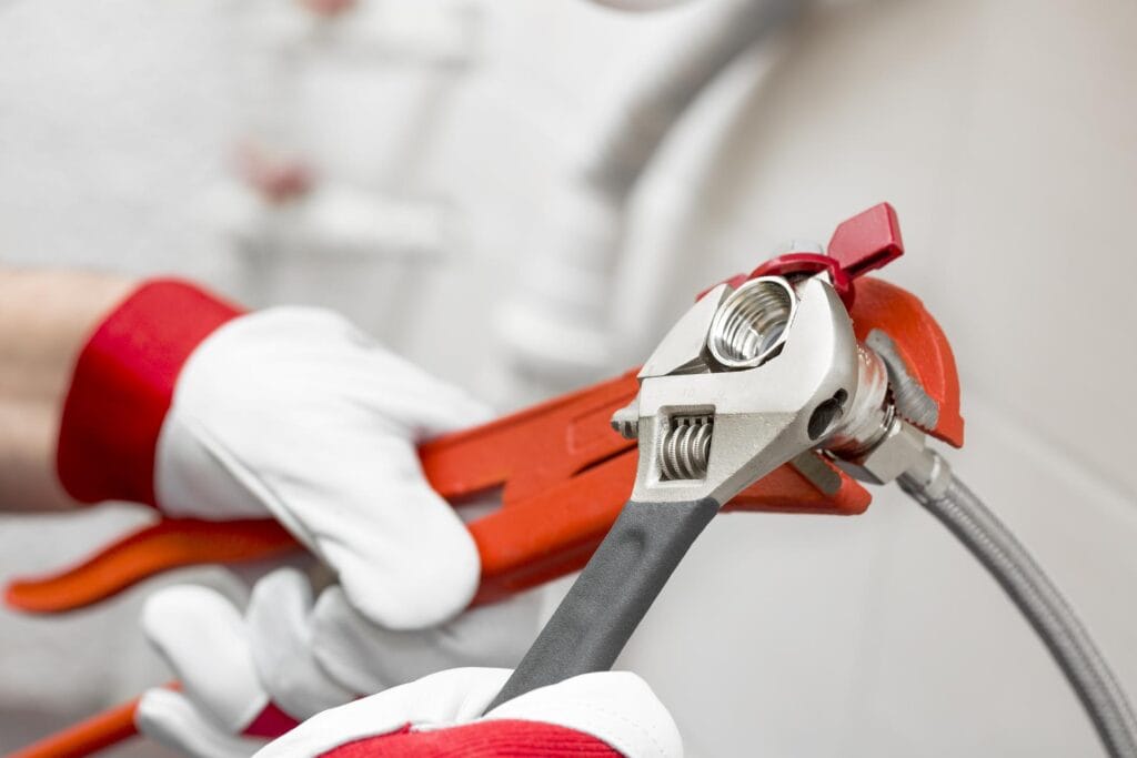 Plumber holding pipe wrenches for an emergency repair in Winder