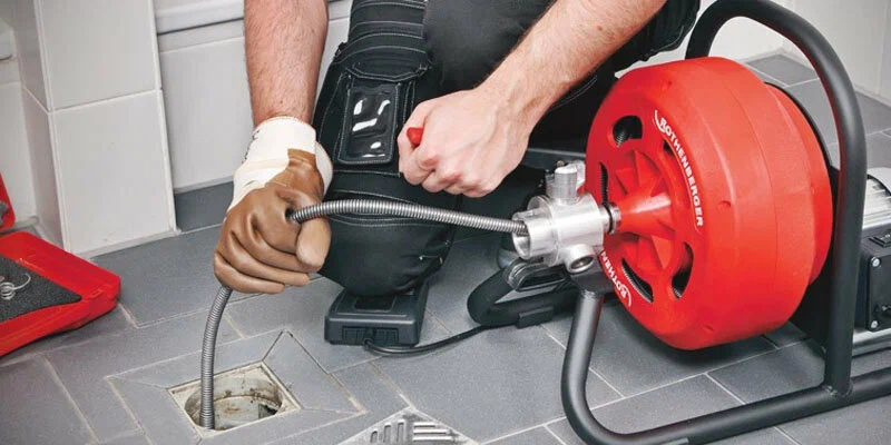 Plumber using a drain-cleaning machine in Winder