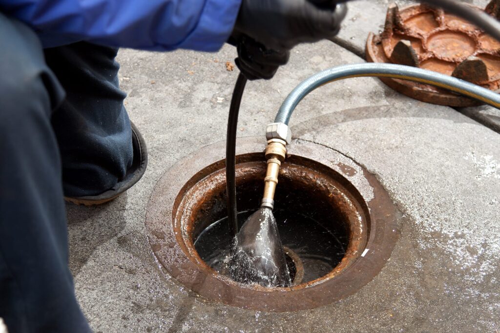Plumber hydro jetting a sewer line through a manhole in Winder