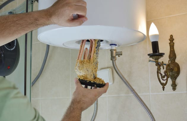 Technician removing mineral buildup from a water heater in Winder
