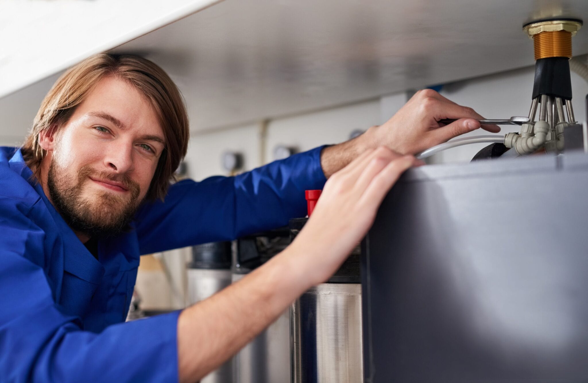 Technician servicing a residential water heater tank in Winder