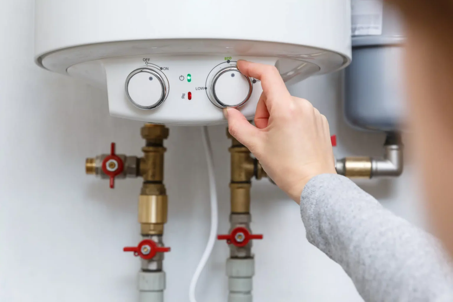 Homeowner adjusting the temperature controls on a water heater in Winder